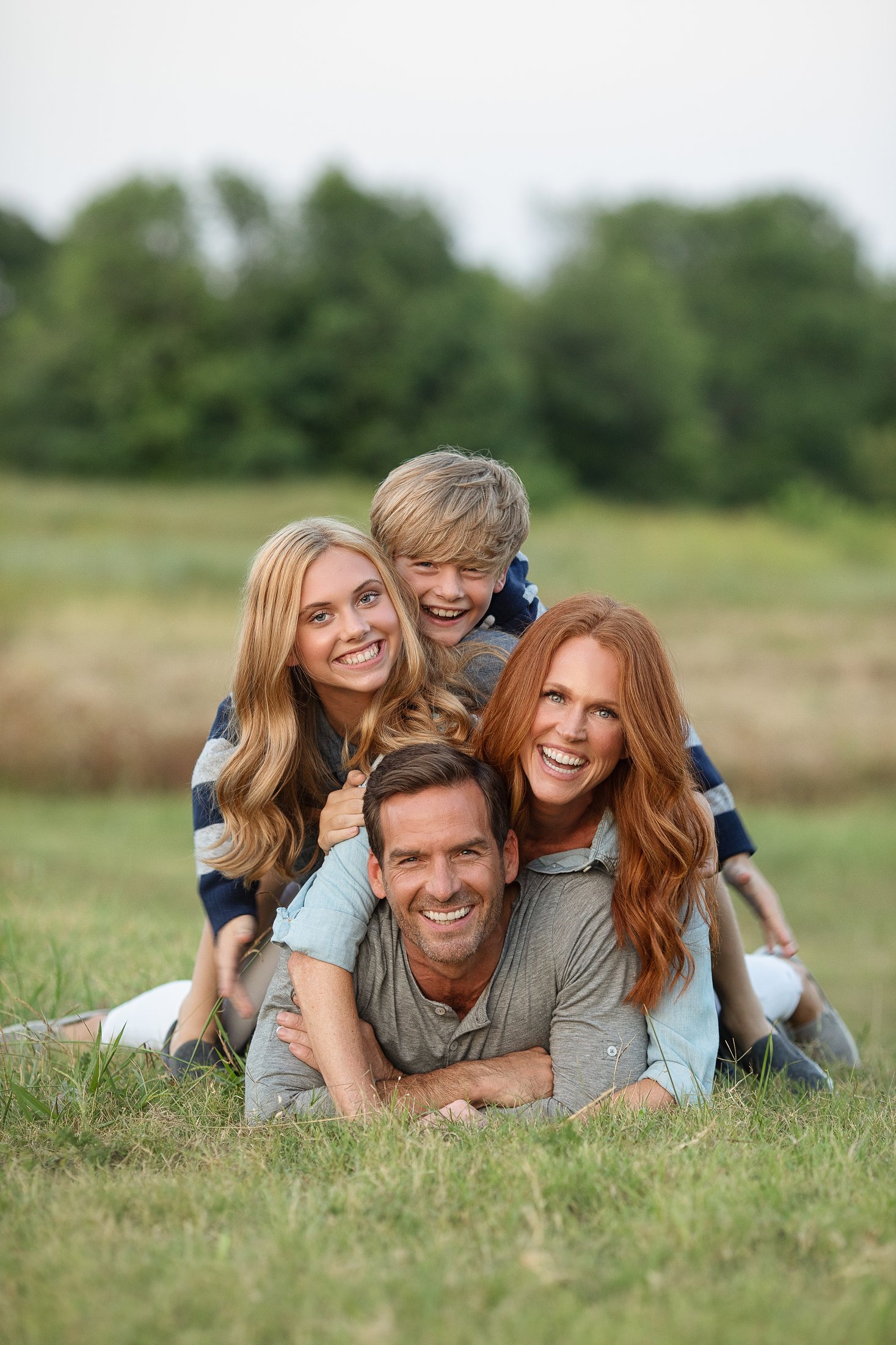 Family piled together laughing in the grass, Dallas family portraits