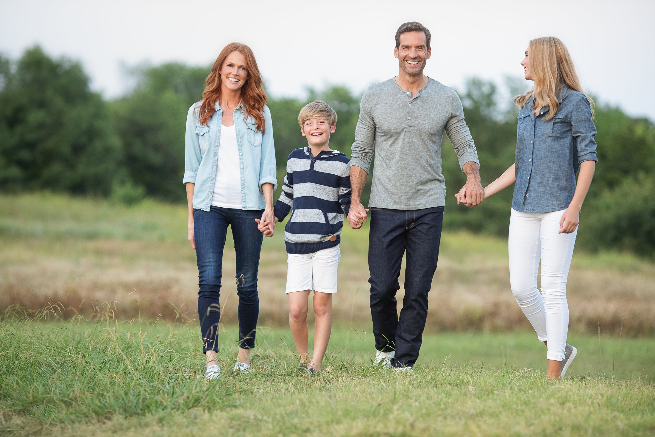 Family walking hand in hand through a field at sunset, Dallas