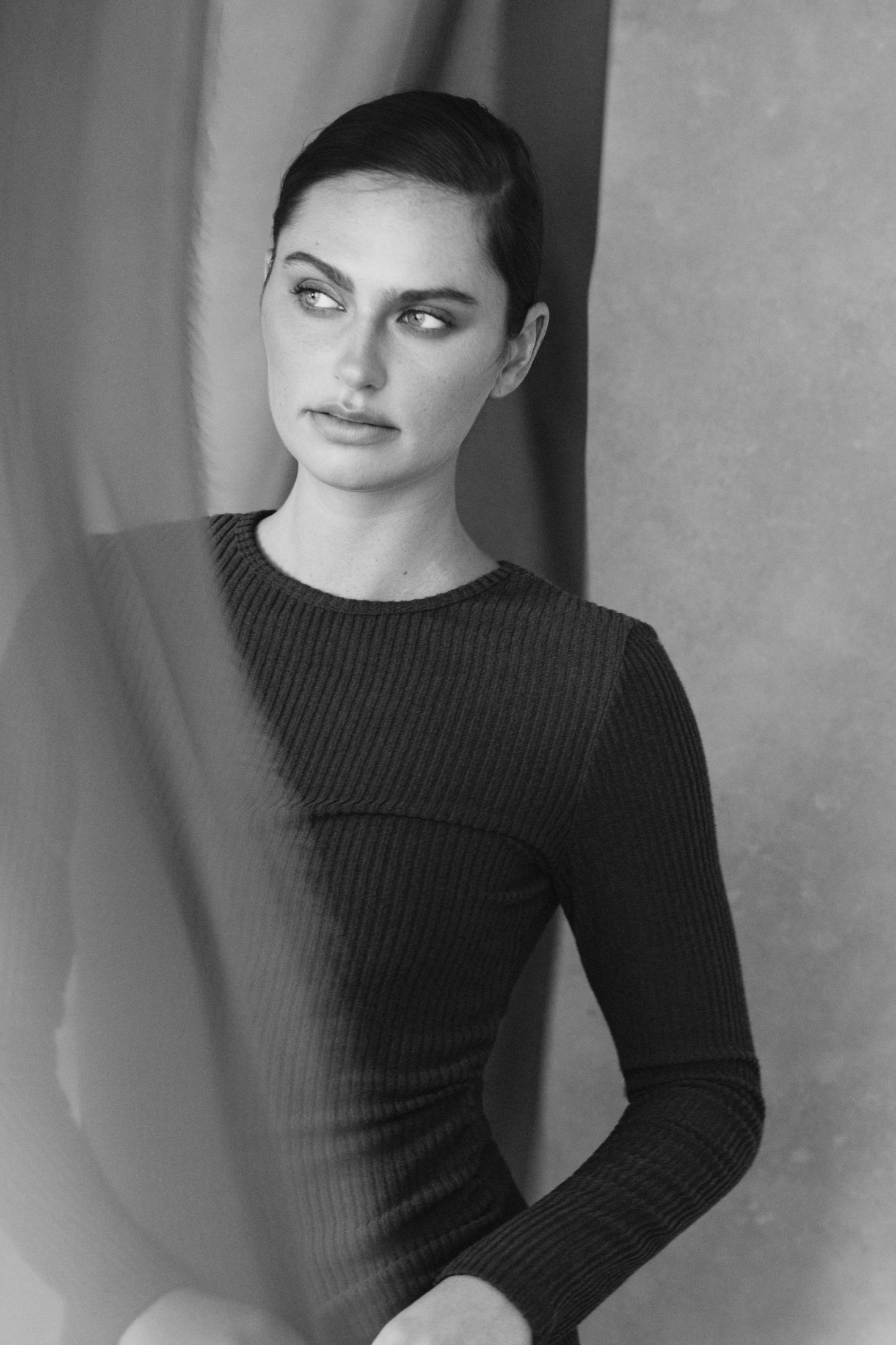Black and white portrait of Isabel Crowe between draped fabric