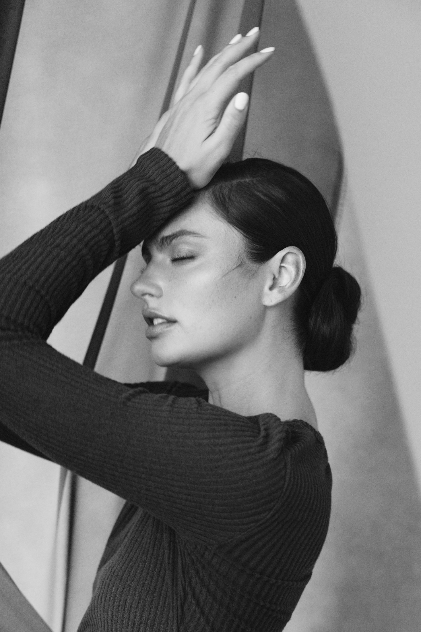 Black and white portrait, hand raised against draped fabric