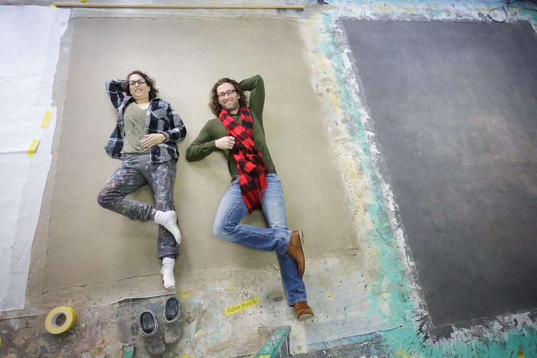 Andrew Knowles and Sarah Oliphant lying on the newly painted green and gold canvas backdrop