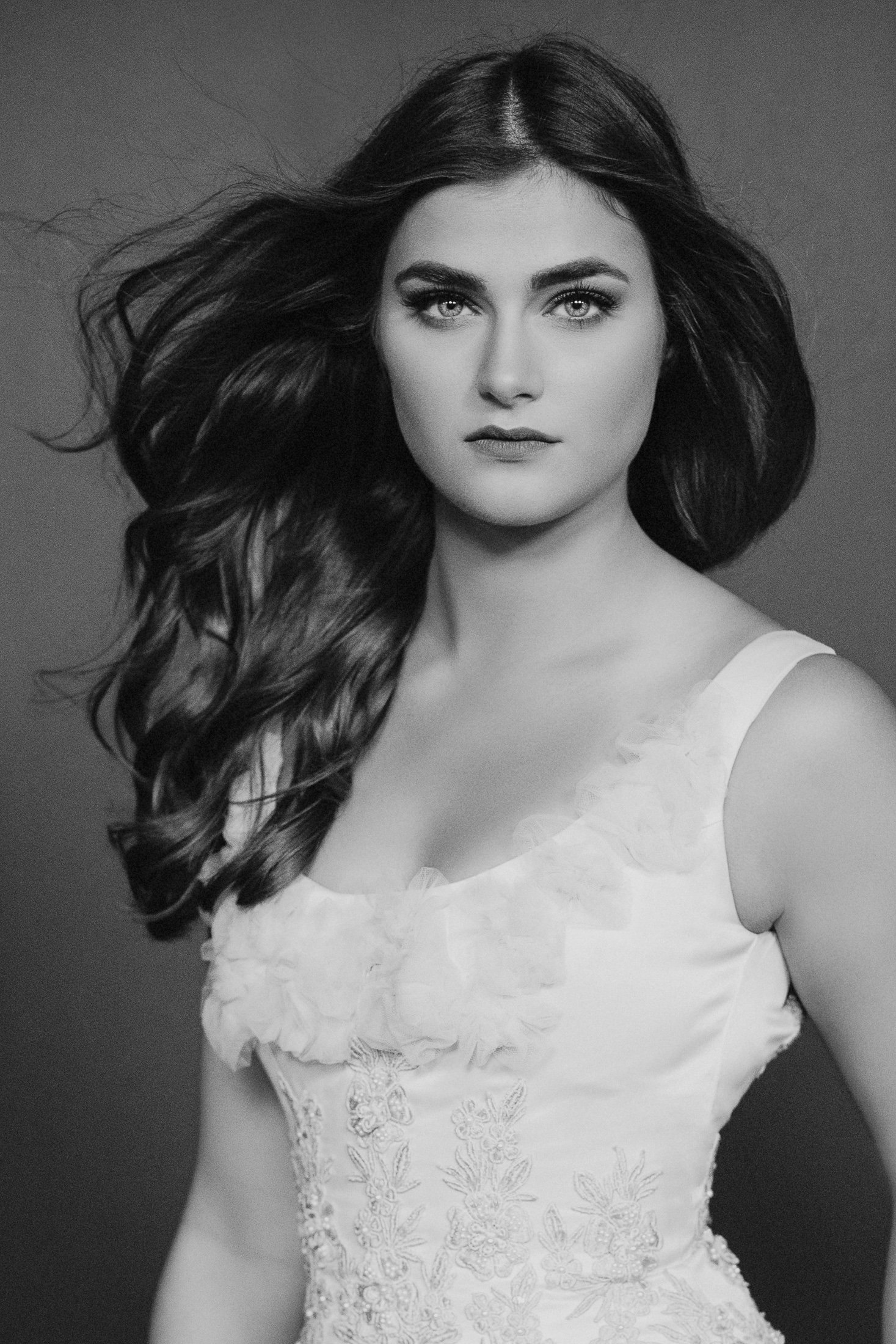 Black and white studio portrait in a white gown, hair in motion, directed sitting at AJK Images Dallas with Sue Bryce