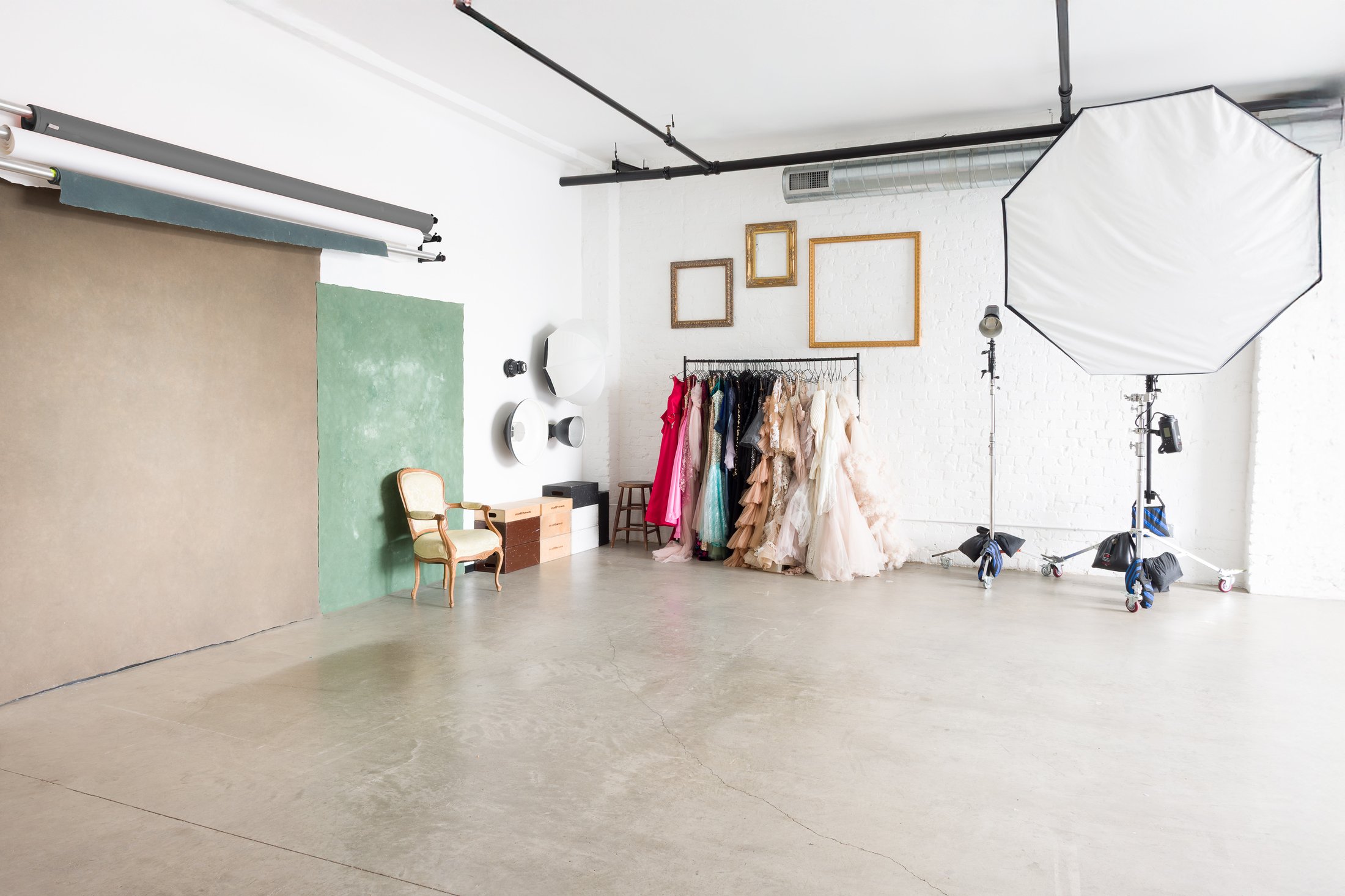 The working studio: painted canvas backdrops, the flower wall, the wardrobe rack, and lighting on stands