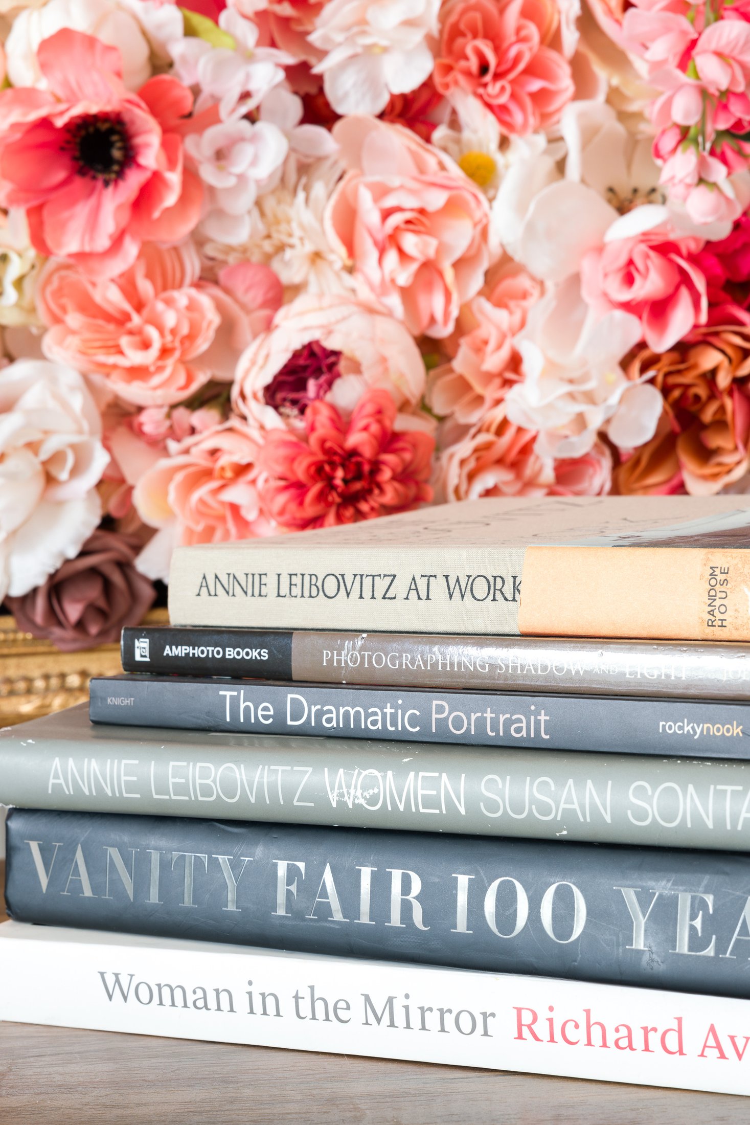 Photography books stacked in front of the flower wall at the AJK Images studio